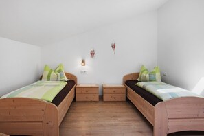 Un dormitorio con dos camas de madera, cada una con una almohada y una mesita de noche.
