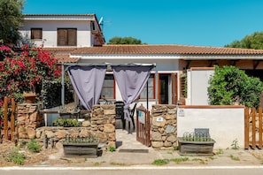 A house with a stone entrance, a number 28 sign, and a covered porch. - San Teodoro Monti 22 – 20 minutes’ walk to the beach, private terrace & air conditioning (San Teodoro)