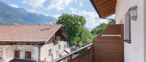 Un balcon doté d’une balustrade en bois, d’où l’on peut admirer un paysage montagneux.