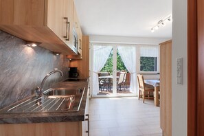 Eine moderne Küche mit integriertem Spülbecken, Holzschränken und Blick auf eine Terrasse.