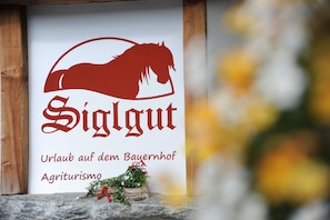 Une enseigne représentant la silhouette d’un cheval et le mot « Siglgut » en rouge, avec un texte en allemand en dessous.