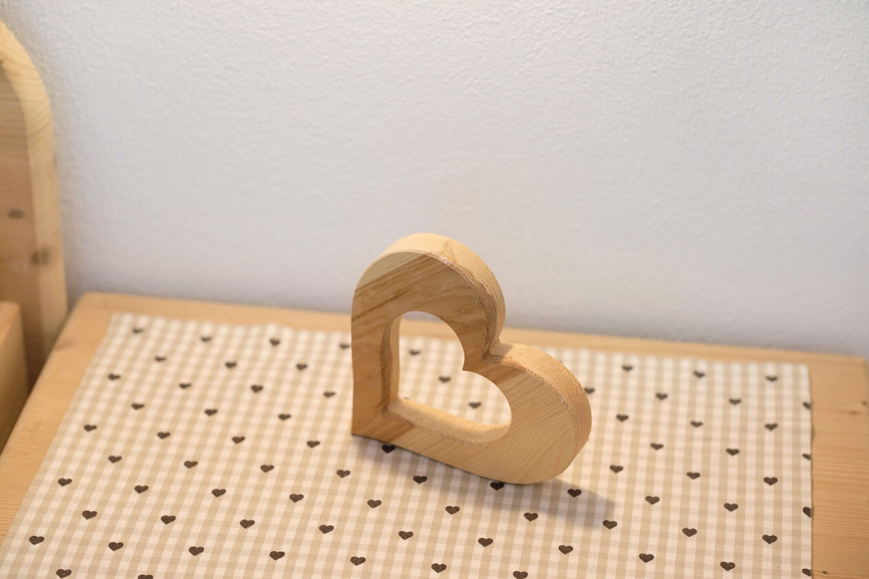 A wooden number 2 with a heart-shaped cutout on a checkered surface.