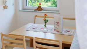 Une table en bois avec un set de table, un vase de fleurs et un livre posé sur la table.