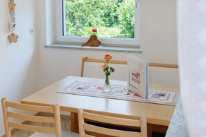 Une table en bois avec un set de table, un vase de fleurs et un livre posé sur la table.