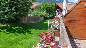 Une terrasse en bois agrémentée de jardinières, une cour clôturée et une vue imprenable sur les montagnes.