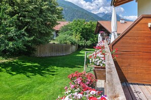 Une terrasse en bois agrémentée de jardinières, une cour clôturée et une vue imprenable sur les montagnes.