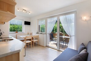 A modern kitchen with a built-in oven, a dining area with a table and chairs, and a sliding glass door leading to an outdoor patio. - Apartment 'Siglgut Ferienwohnung Wendy' with Mountain View, Shared Terrace and Wi-Fi (Tarsch)