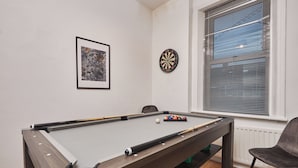 A pool table with balls, a dartboard, a framed picture, and a window with blinds. - Ladykirk Road (Newcastle-upon-Tyne)