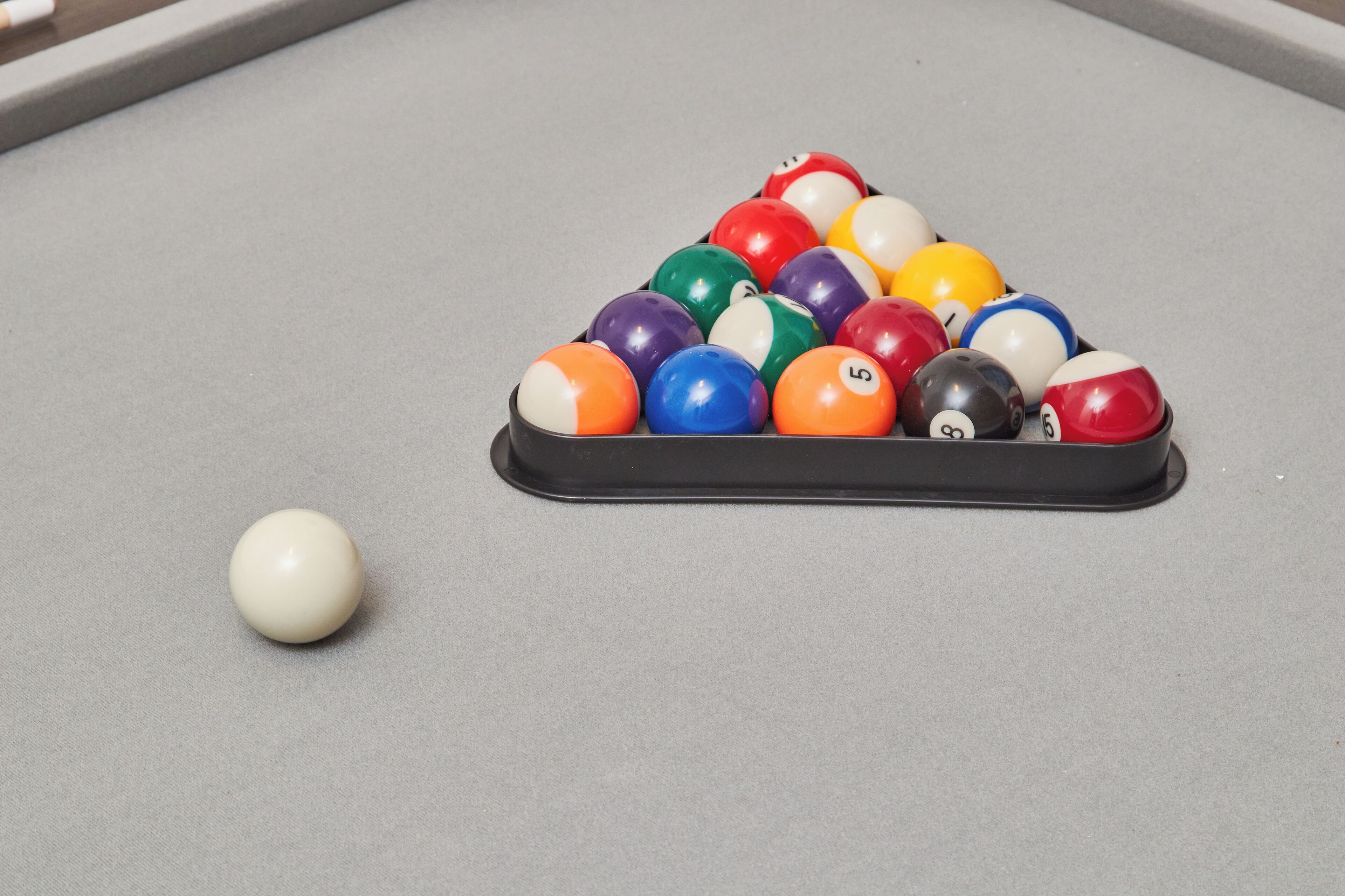 A pool table with a triangular rack of billiard balls and a single ball on the table.