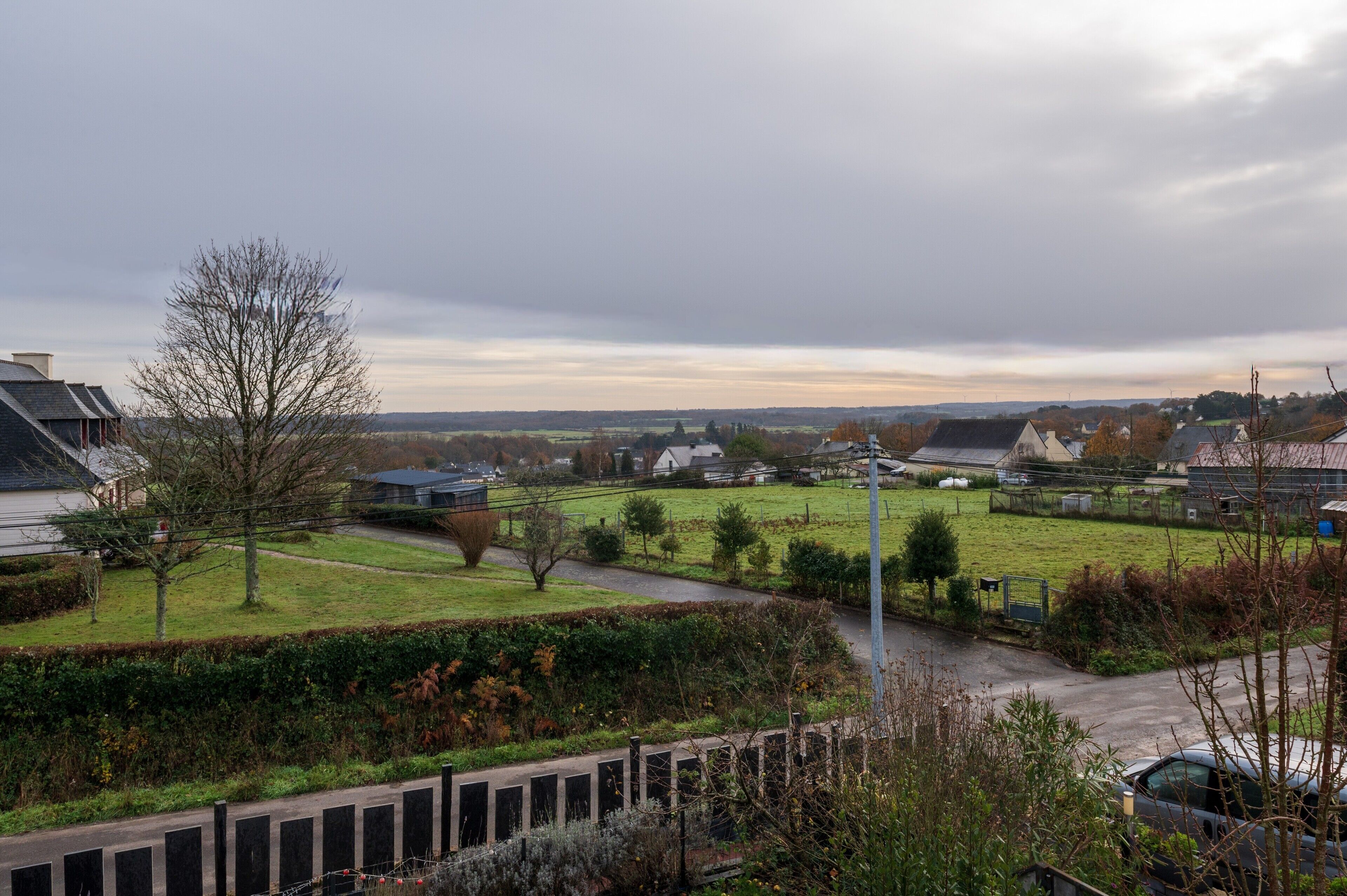A residential area with houses, a grassy field, and a paved road.