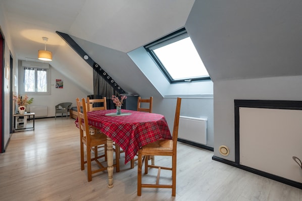 Un coin repas avec une table dressée pour quatre personnes, une lucarne et une vue sur l’extérieur.