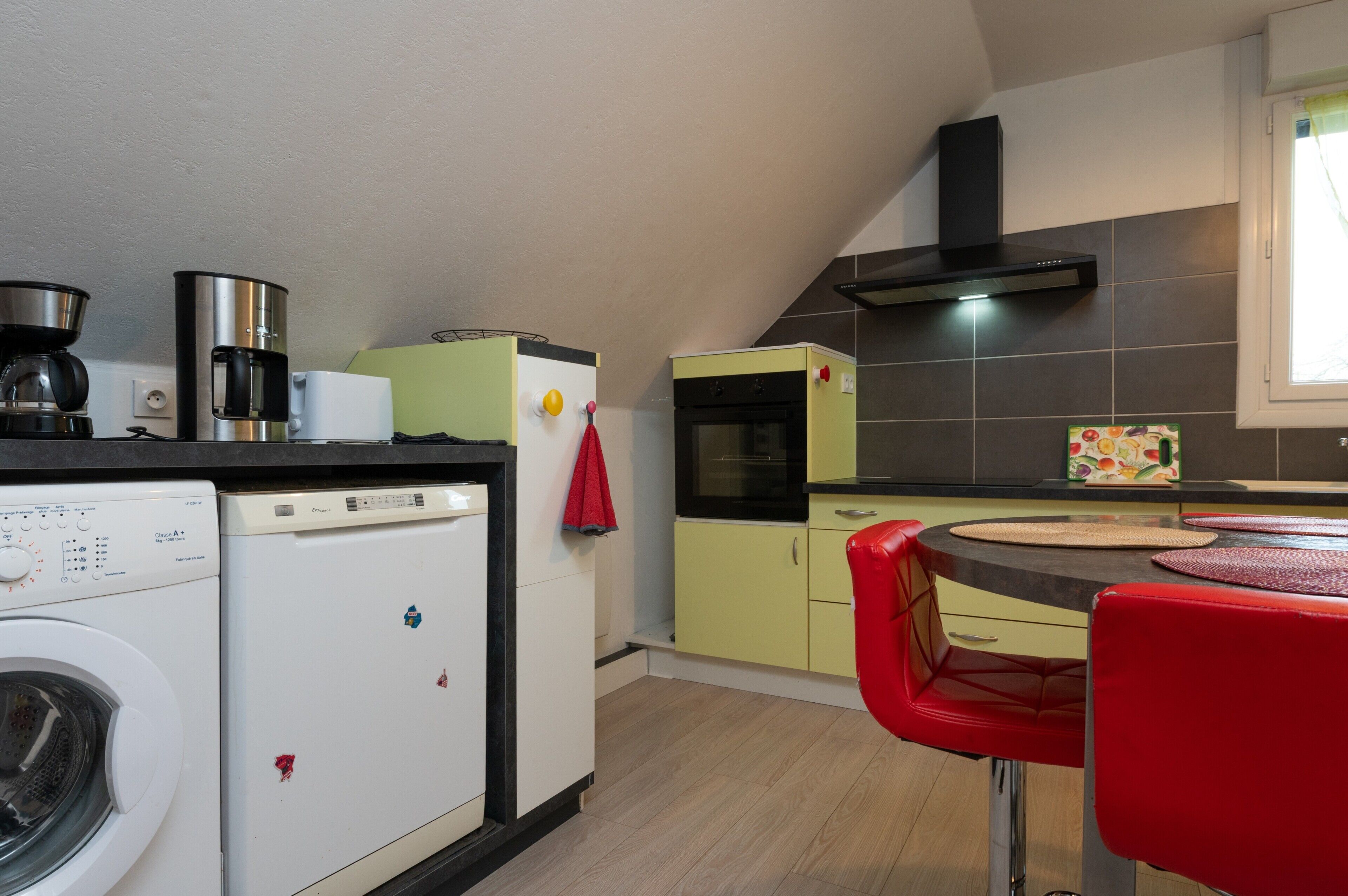 Cocina compacta con lavadora, cafetera, microondas y horno pequeño.
