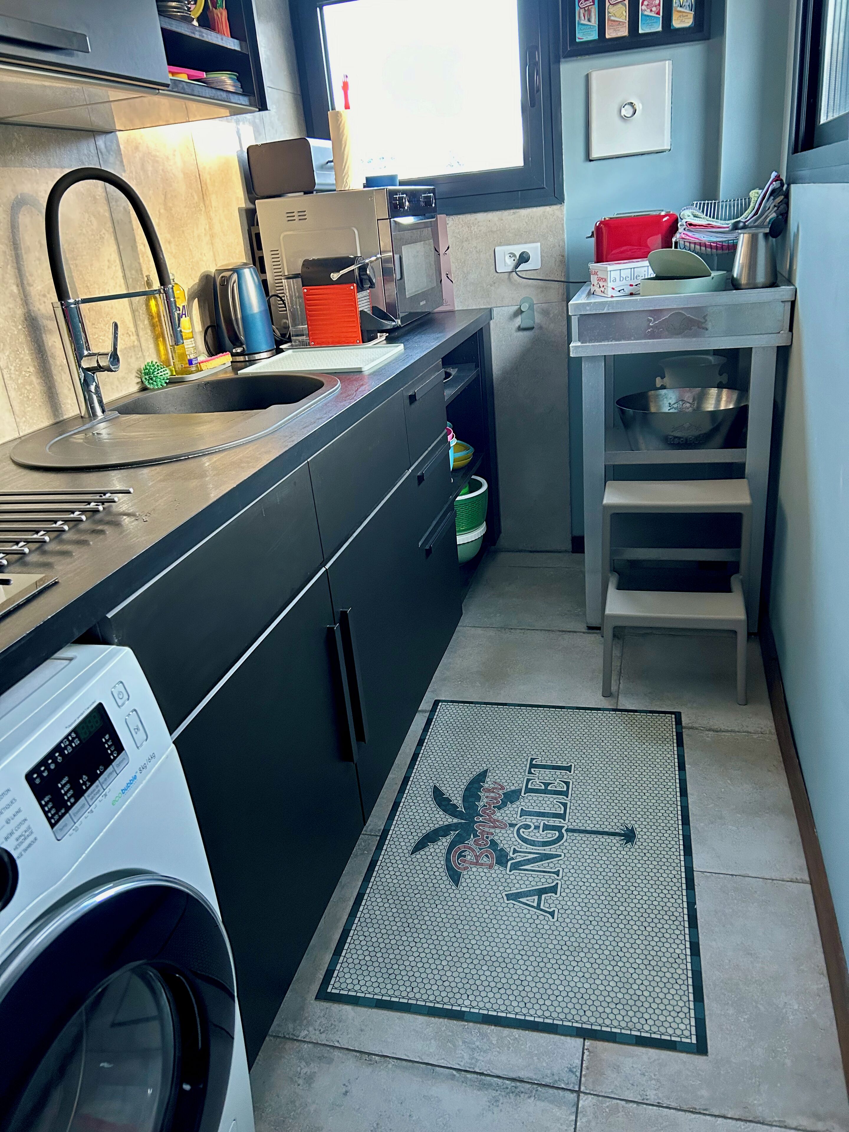 A compact kitchen with a washing machine, a sink, and a small countertop.