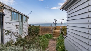 Ein Weg führt zu einem Strand mit einer Treppe und Blick aufs Meer.