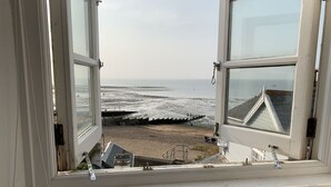 Blick aus einem Fenster auf einen Strand mit einem Pier und einem Gebäude im Hintergrund.