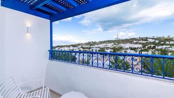 Een balkon met een blauwe reling, witte stoelen en een tafel.