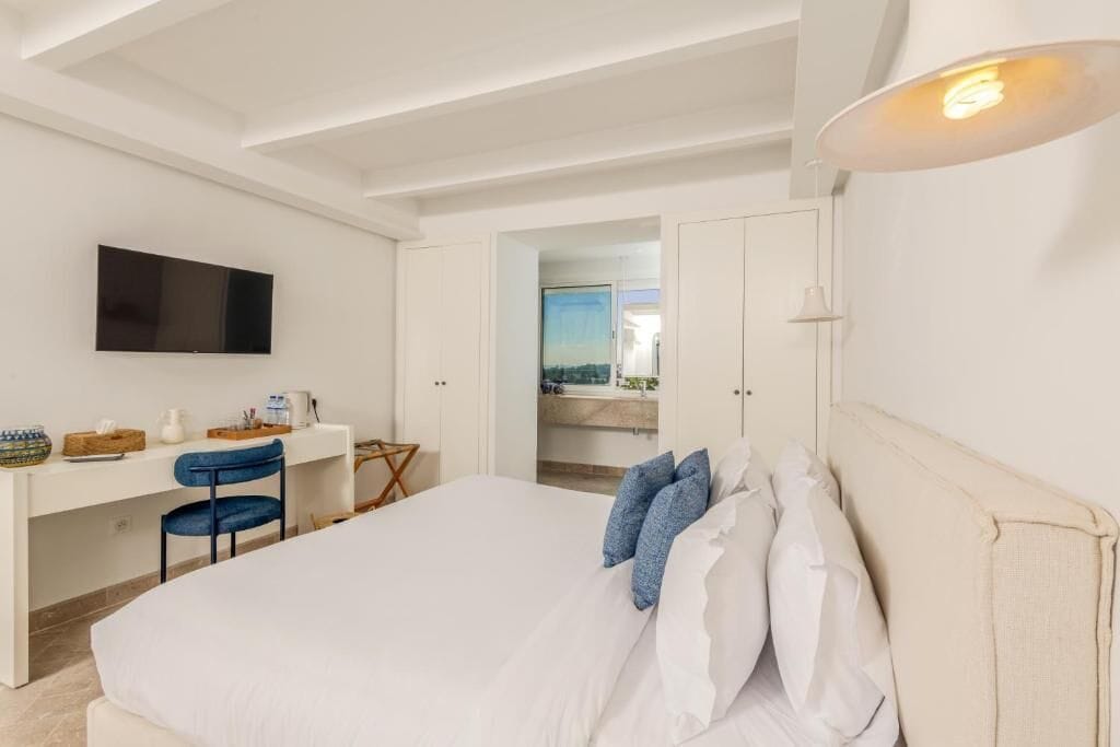 Una habitación de hotel moderna con una cama grande, un escritorio y un televisor.