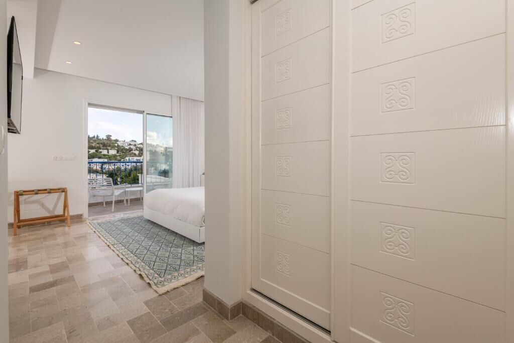 Habitació d'hotel moderna amb llit, vistes a la ciutat i un gran finestral.