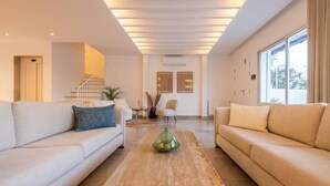 A modern living room with a sofa, coffee table, and a staircase leading to another level.