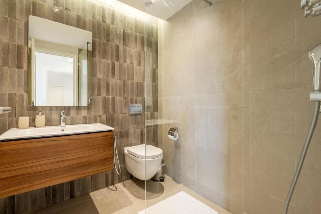 A modern bathroom with a wooden vanity, a glass shower enclosure, and a large mirror.