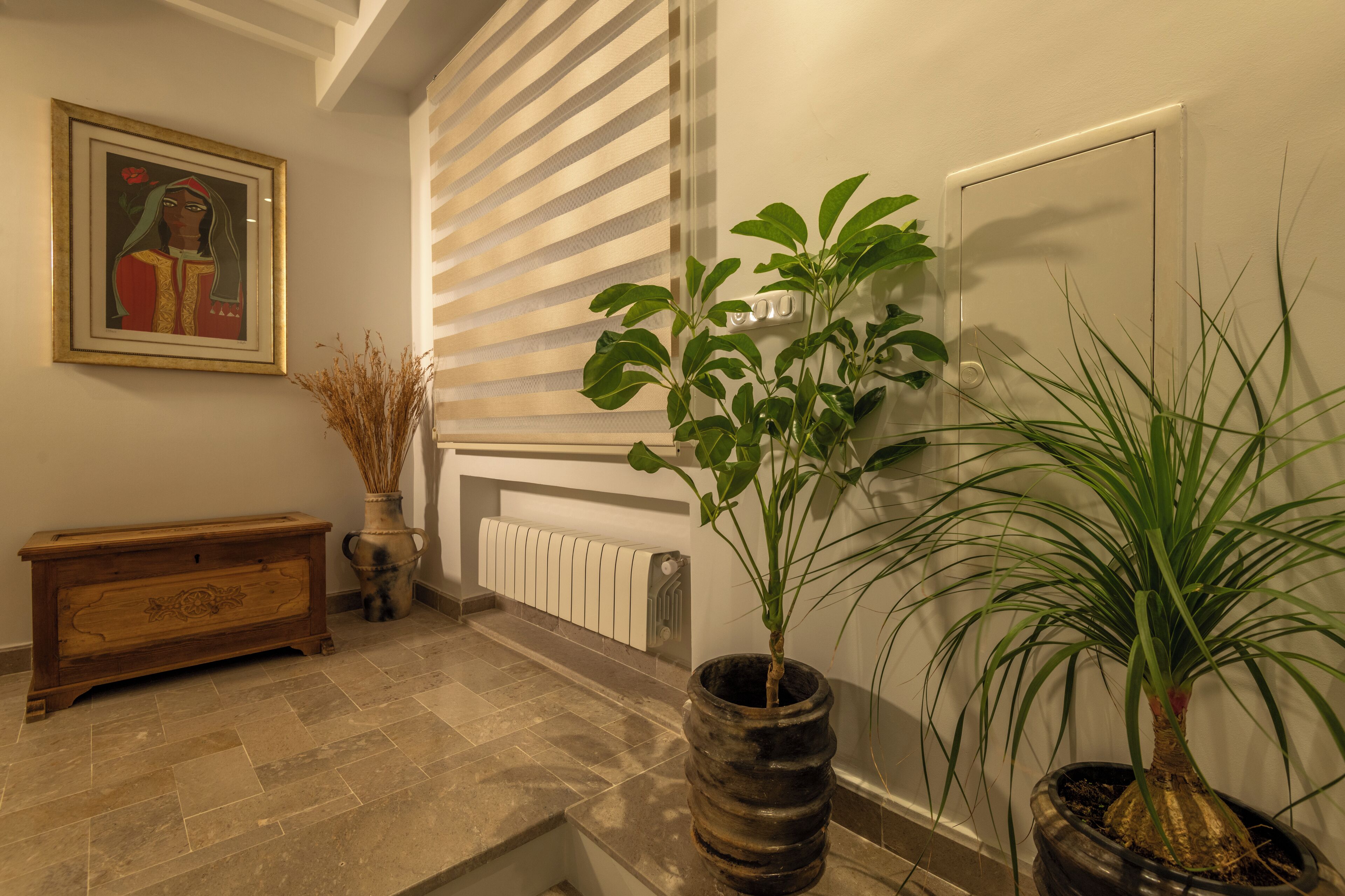 A hallway with a radiator, a wooden bench, and two potted plants.