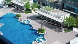 A modern hotel with a large outdoor swimming pool, sun loungers, and a covered seating area. - Chic 1BR Apartment - The Crest Dubai (Dubai)