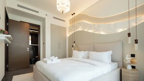 A modern hotel room with a large bed, a wooden wardrobe, a bathroom, and a small side table with a vase. - Chic 1BR Apartment - The Crest Dubai (Dubai)
