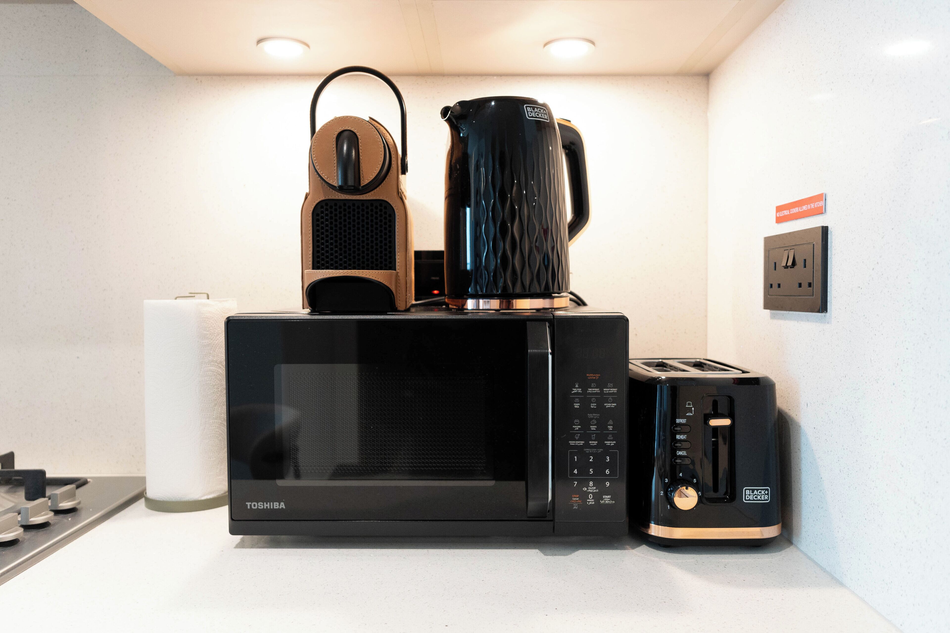 A kitchen with a black microwave, toaster, and coffee maker on the counter.
