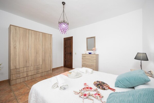 A bedroom with a large wardrobe, a bedside table with a lamp, and a bed with towels and a bathrobe. - Villa Baena - Four Bedroom Villa, Sleeps 8 (Macaca)