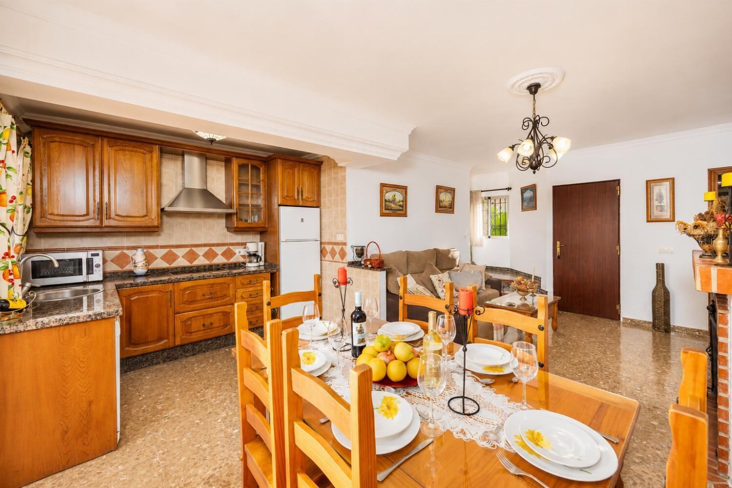 A dining area with wooden furniture, a kitchen with wooden cabinets, and a dining table set for a meal.