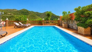 A rectangular swimming pool with clear blue water, surrounded by a brick deck, lounge chairs, and potted plants. - Villa Alvarez - Three Bedroom Villa, Sleeps 6 (Almuñécar)