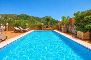 A rectangular swimming pool with clear blue water, surrounded by a brick deck, lounge chairs, and potted plants. - Villa Alvarez - Three Bedroom Villa, Sleeps 6 (Almuñécar)