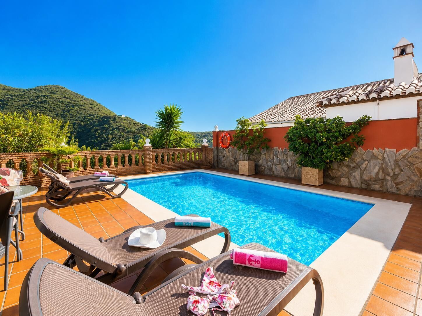 Une piscine avec des chaises longues, une table et une vue sur une montagne.