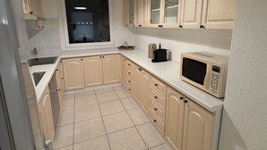 A kitchen with beige cabinets, a microwave, and a window.
