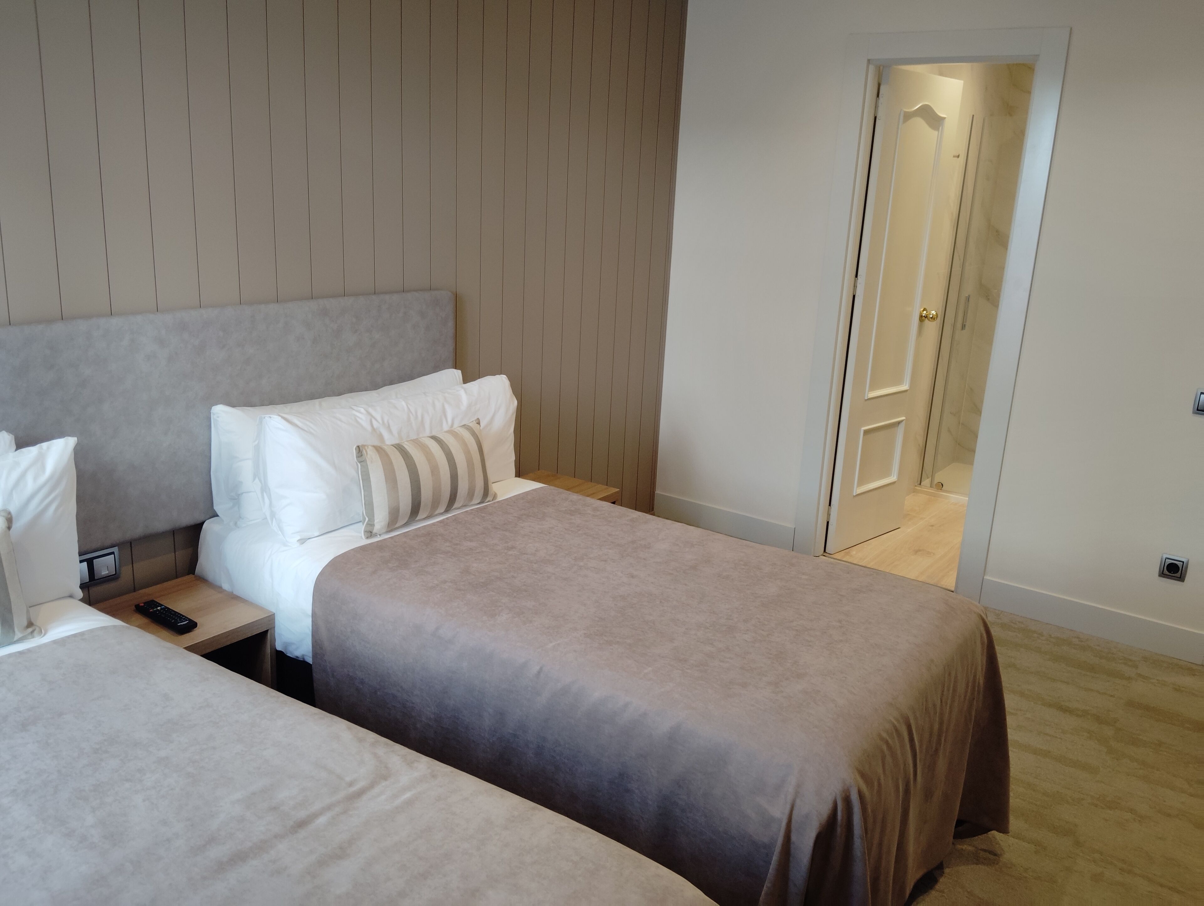 Una habitación de hotel con dos camas, una mesita de noche y una puerta que da a un baño.