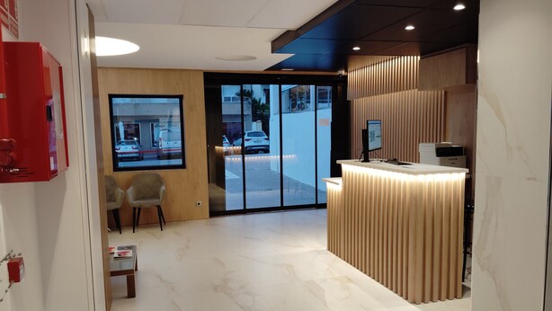 Ett välkomnande område med modern design, som inkluderar en receptionsdisk, en sittgrupp och utsikt över gatan utanför.