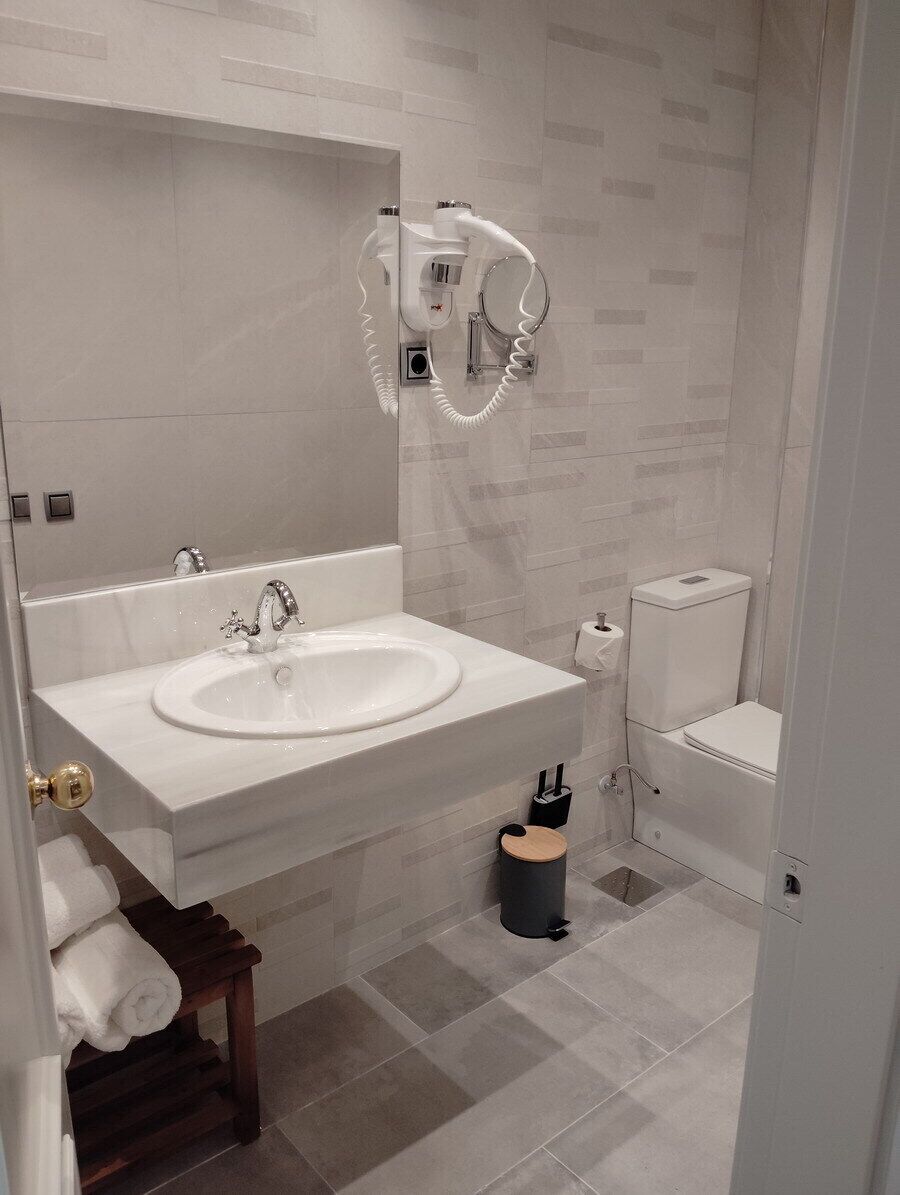 A modern bathroom with a large sink, a toilet, and a towel rack.