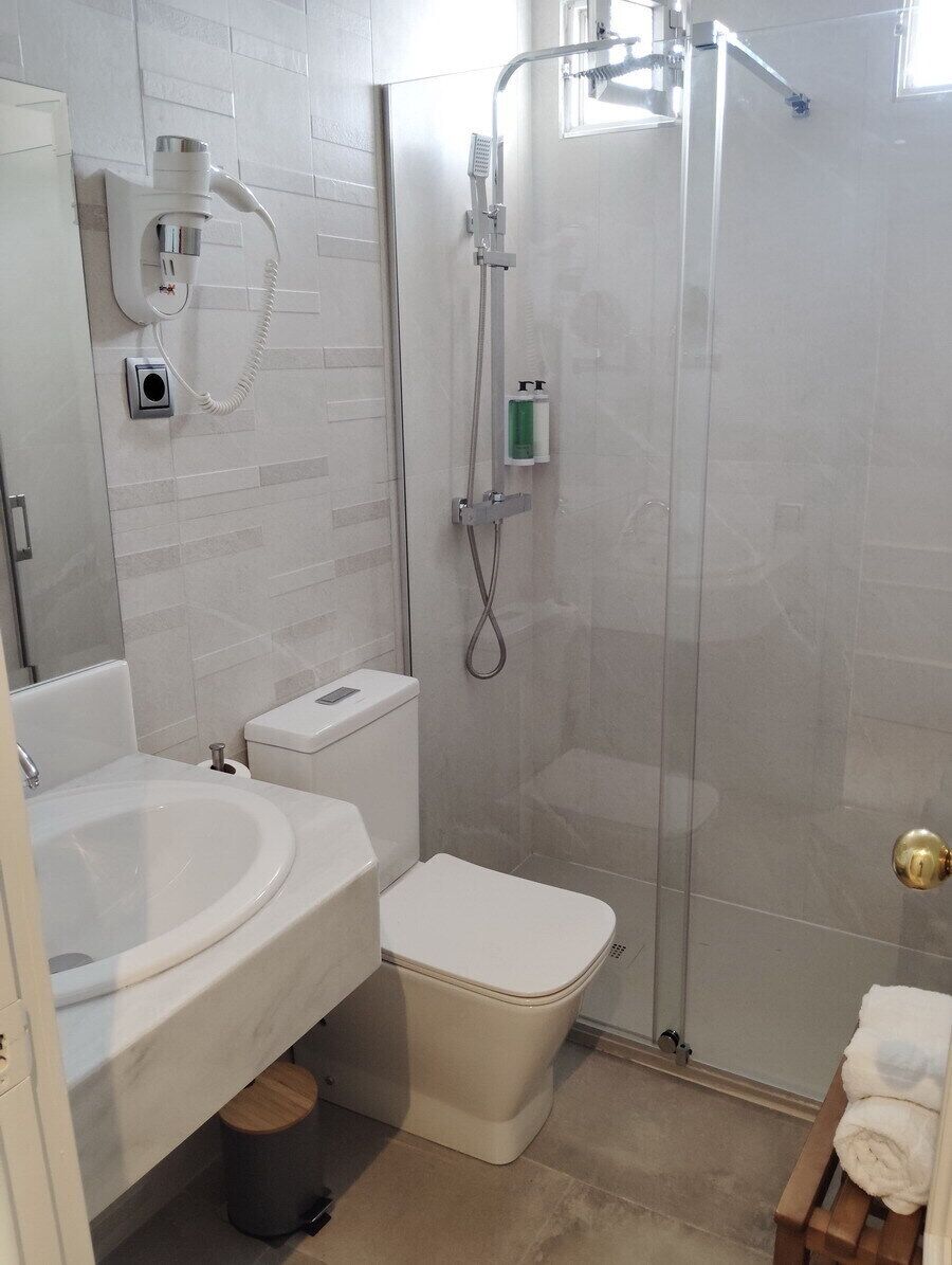 Une salle de bain comprenant des toilettes, un lavabo, une douche et un espace de douche vitré.