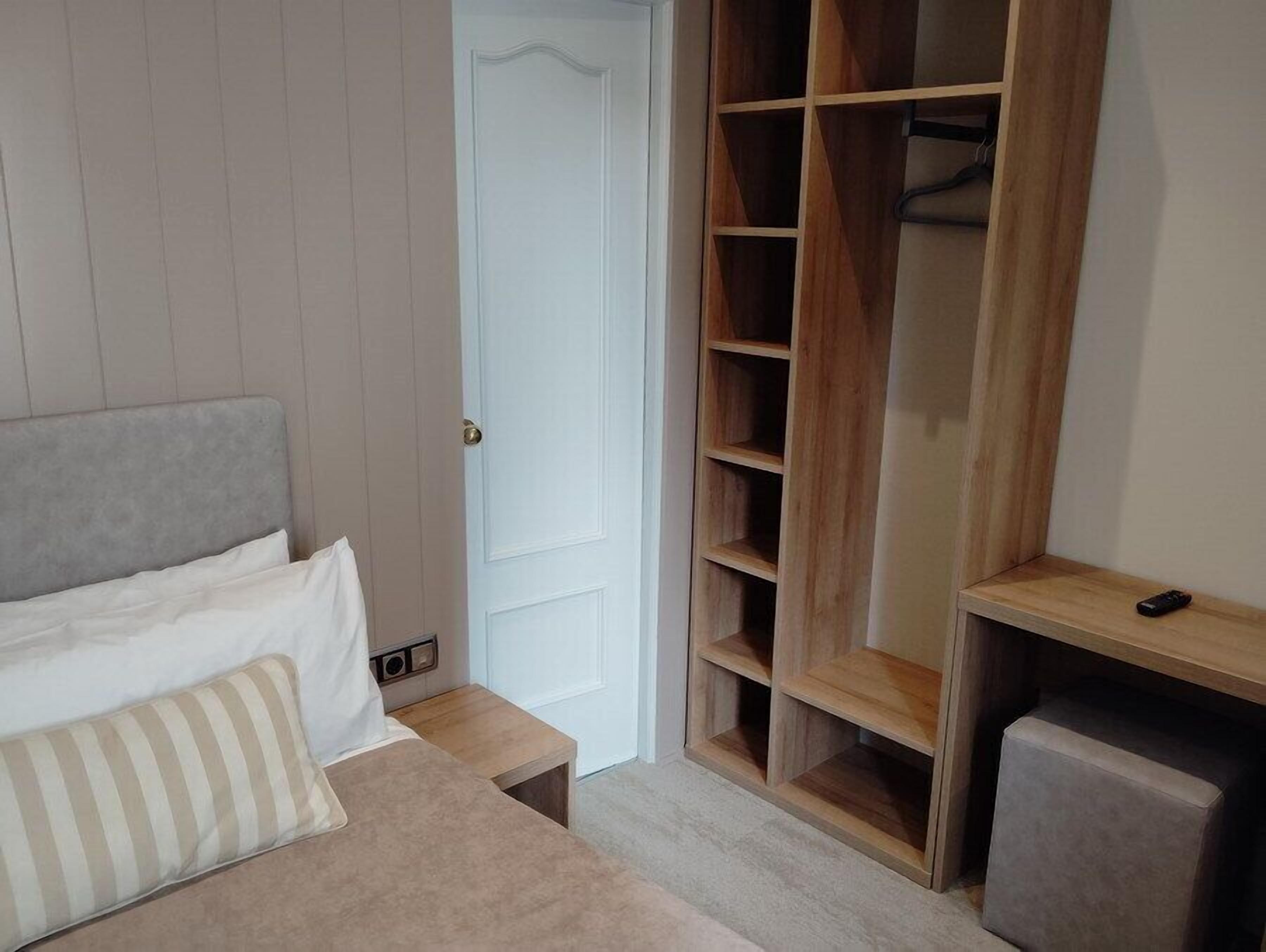 A bedroom with a bed, a wooden wardrobe, a nightstand, and a small table.