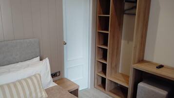 Un dormitorio con cama, armario de madera, mesita de noche y una pequeña mesa.