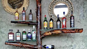 A bar setup with various liquor bottles and glasses on wooden shelves and a wooden counter.