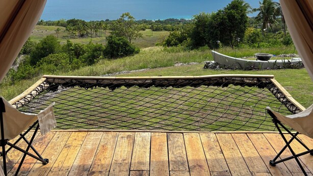 A wooden deck with a view of the ocean and greenery.