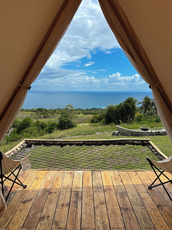 A wooden deck with a view of the ocean and greenery.