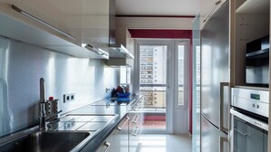A modern kitchen with stainless steel appliances, a large sink, and a view of the city through a glass door. - Brussels Expo Elegant residence (Brussels)