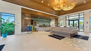 A modern lobby with a wooden ceiling, a reception desk, and a view of the outdoors. - Themed 5BR Home + Pool at Windsor Cay (Clermont)