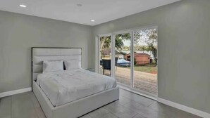 Une chambre dotée d’un grand lit, d’une porte-fenêtre coulissante donnant sur l’extérieur et d’un plafond équipé de spots encastrés.