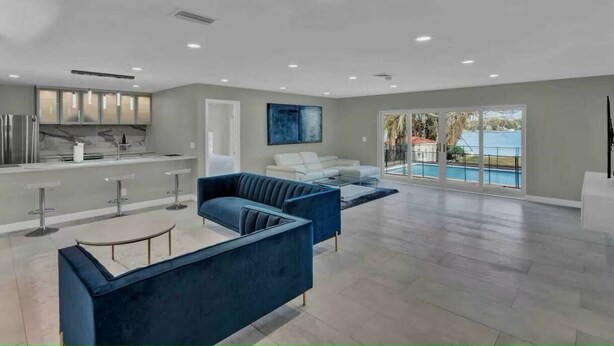 Un grand espace de vie avec vue sur la piscine, un mobilier moderne et un coin cuisine.