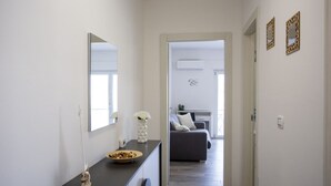 A modern hallway leading to a bedroom with a bed, a desk, and a chair. - Sea Apartment - with shared Pool (Villaggio del Golfo)