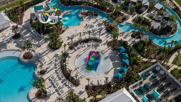 Vue aérienne d’un complexe hôtelier doté de plusieurs piscines, de toboggans aquatiques et de chaises longues.
