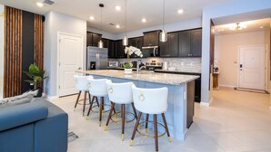 Una cocina moderna con armarios oscuros, una isla grande con taburetes de bar y electrodomésticos de acero inoxidable.